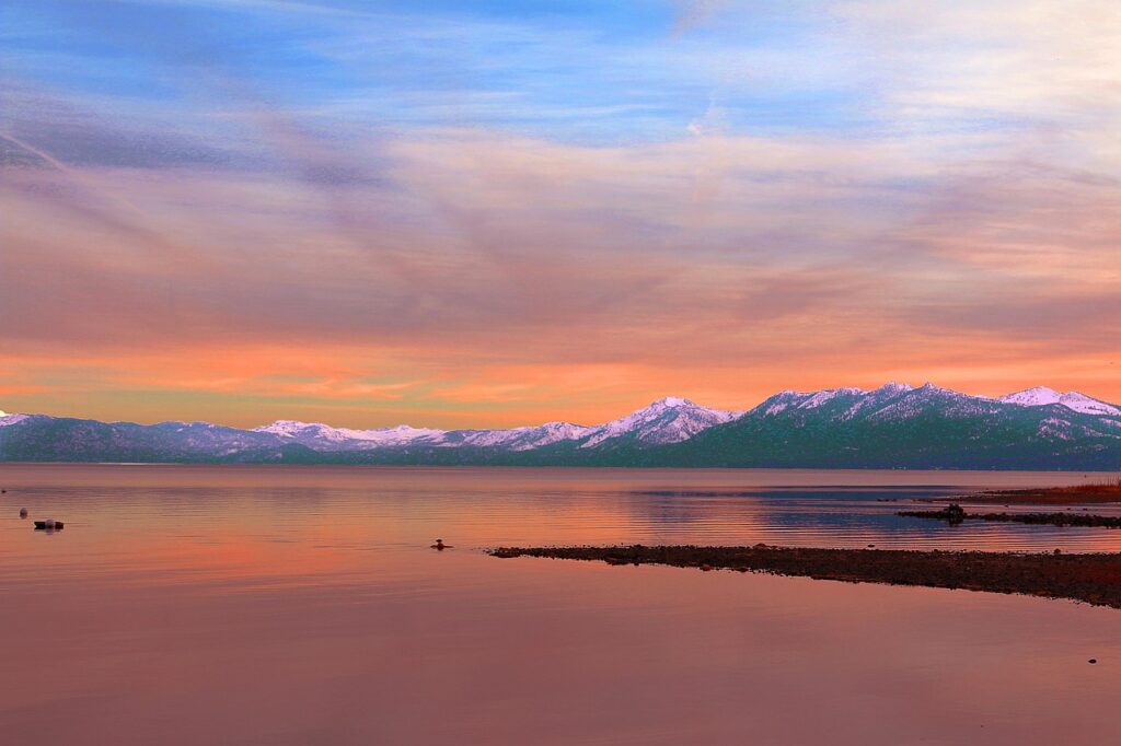 snow on mountains over lake